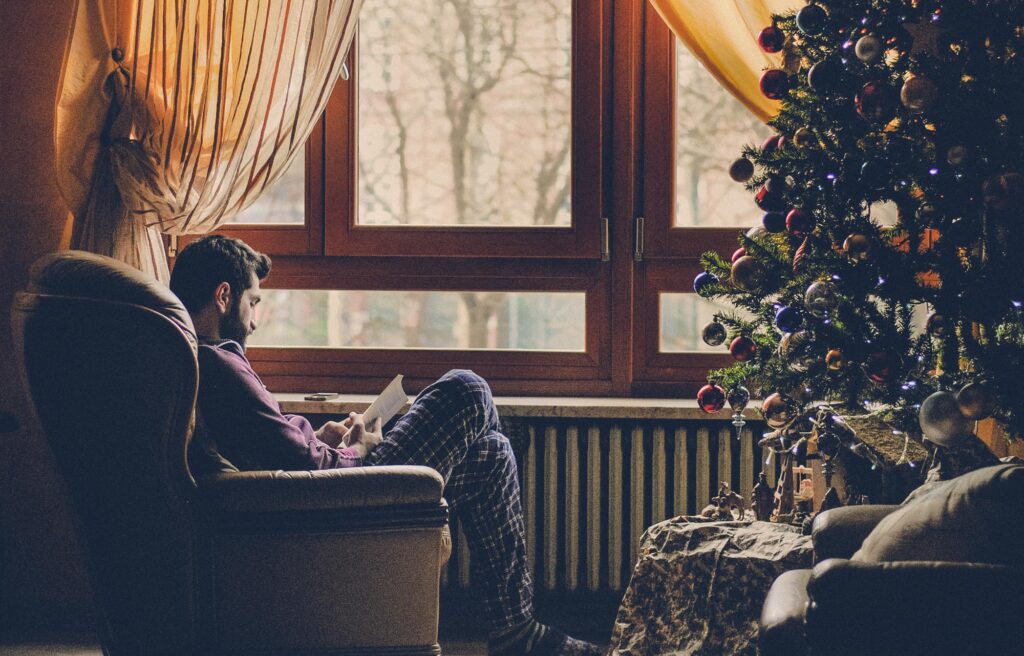 Persona leyendo un libro y reflexionando en un ambiente navideño